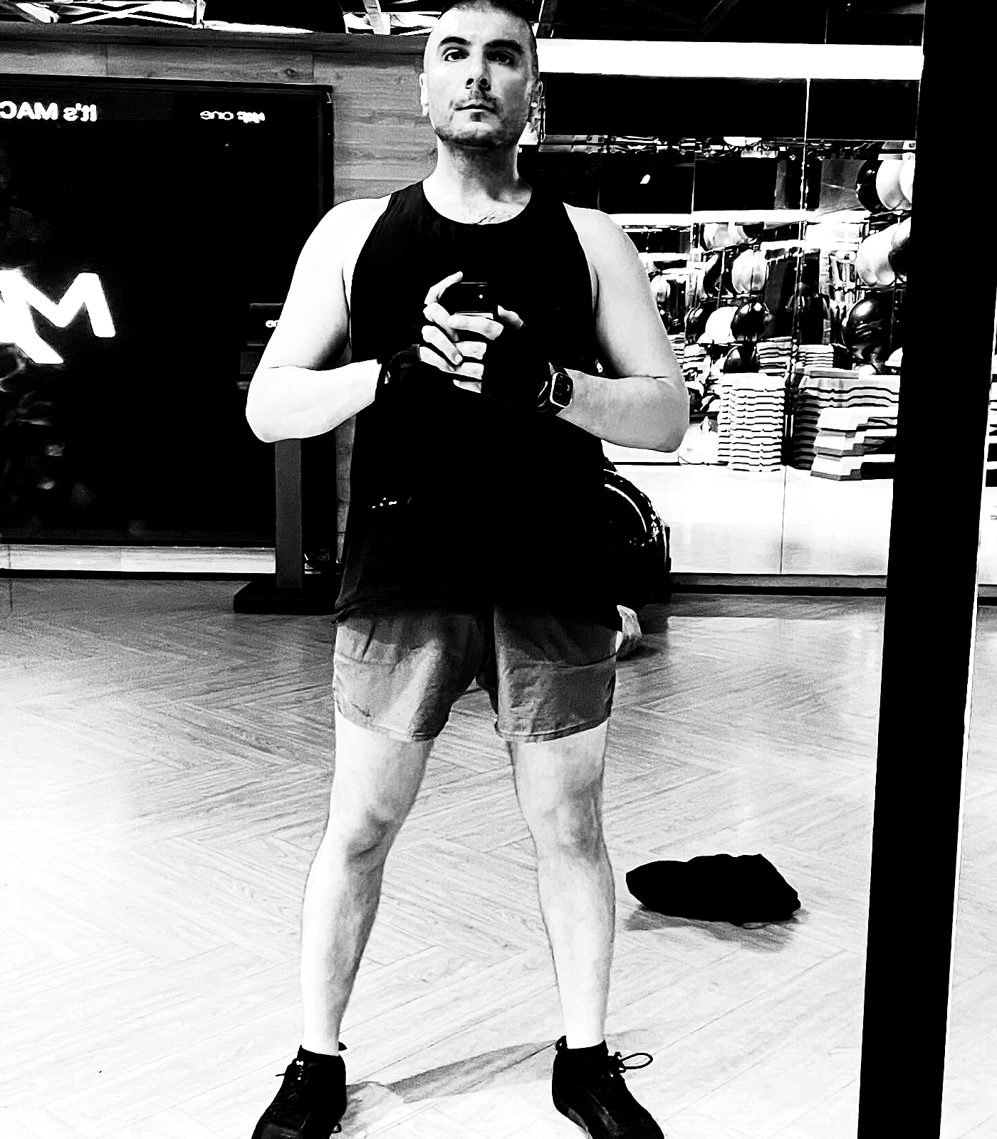 A cropped mirror study of torso, arms, and shorts on a bright gym floor, with glove and fabric edges emphasized by the xerox treatment.